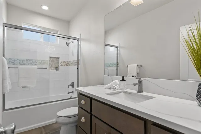 a bathroom with a double vanity sink toilet mirror and shower