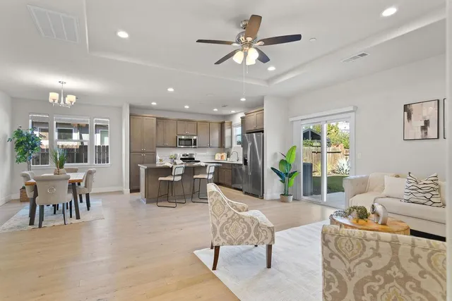 a living room with furniture kitchen view and a chandelier