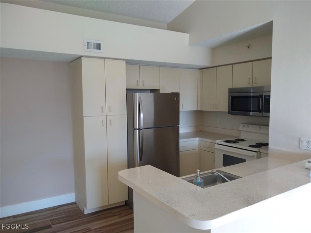 13521 Eagle Ridge Drive, Unit 128 Fort Myers, FL 33912 - Photo 2 of 11 a kitchen with stainless steel appliances granite countertop a refrigerator and a stove top oven