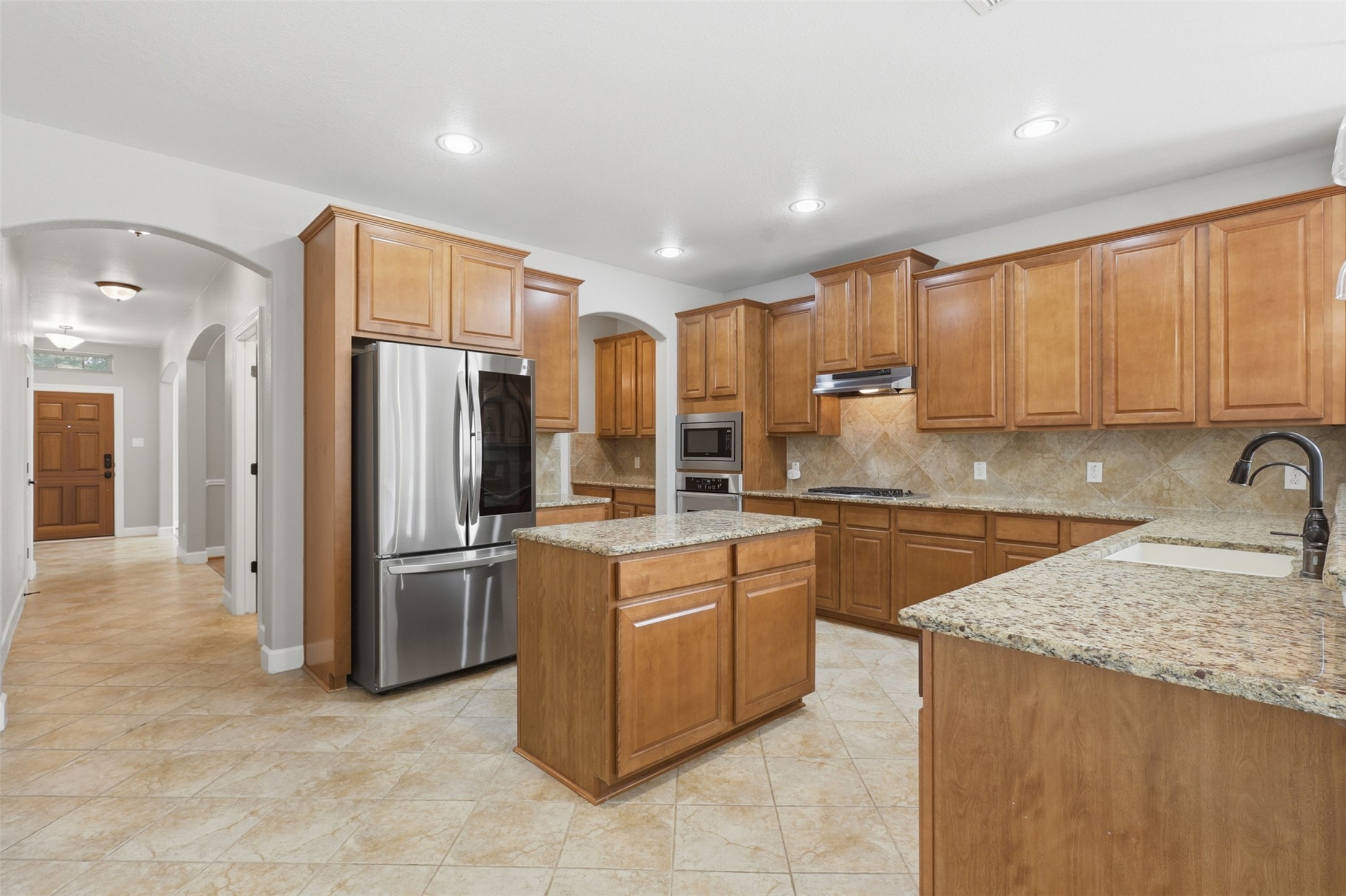 721 Rufina Street League City, TX 77573 - Photo 7 of 33 The heart of the home is a beautifully appointed gourmet kitchen showcasing rich 42-inch wood cabinetry, gleaming granite countertops, a spacious center island, stainless steel appliances, and a timeless tile backsplash.