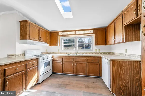 a kitchen with stainless steel appliances granite countertop a refrigerator a sink dishwasher a stove with wooden cabinets and floor