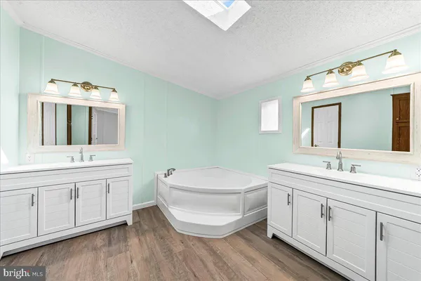 a bathroom with a double vanity sink mirror and bathtub