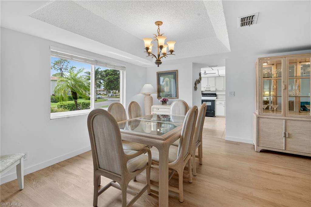 219 Memory Lane, Unit 3 Naples, FL 34112 - Photo 17 of 35 Dining area with a tray ceiling, wood finish floors, and a chandelier