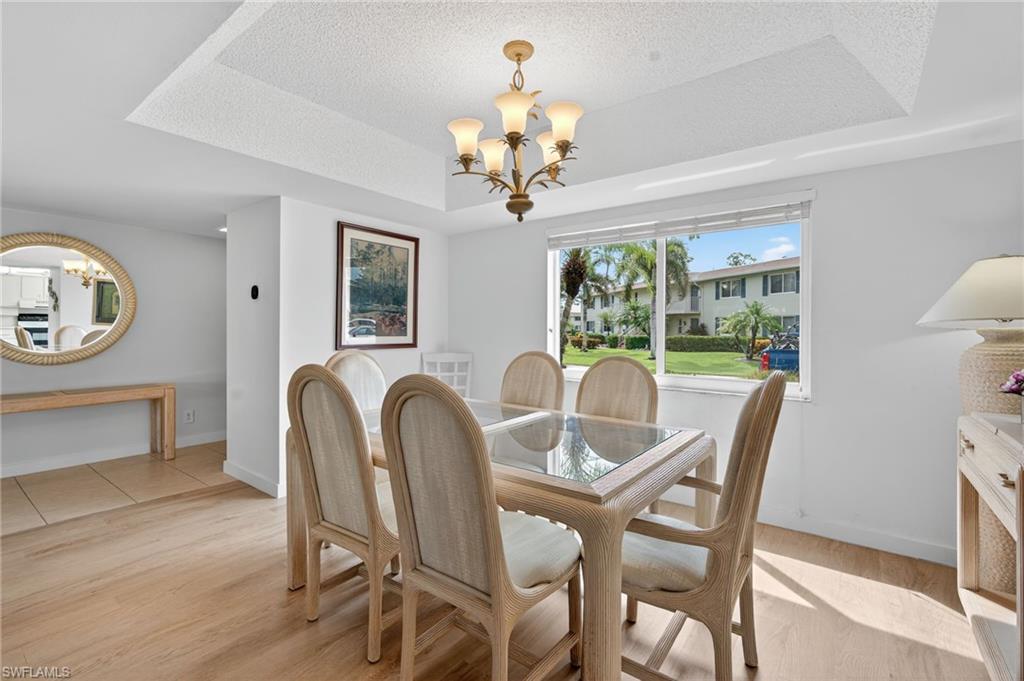 219 Memory Lane, Unit 3 Naples, FL 34112 - Photo 20 of 35 Dining space with a chandelier, a tray ceiling, and light wood-style floors