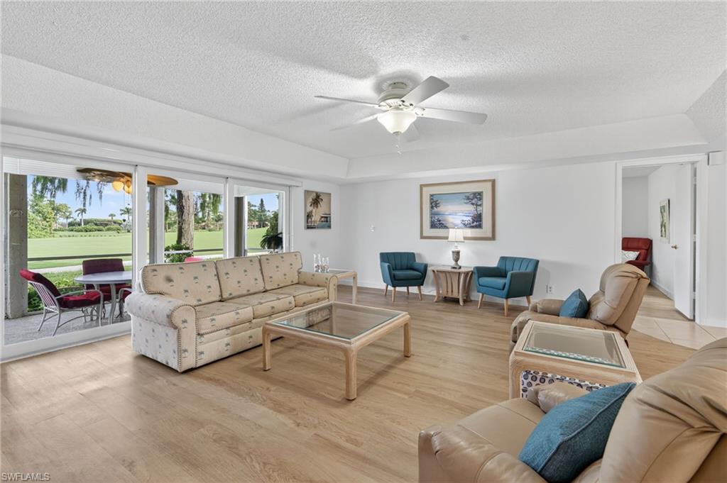 Living area featuring a ceiling fan, light wood-style flooring, and a tray ceiling