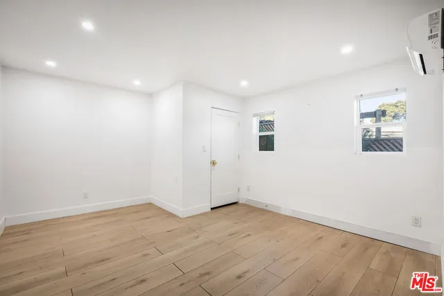an empty room with wooden floor and window