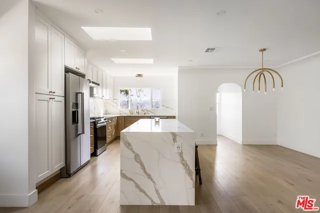 a view of a kitchen with a sink refrigerator and wooden floor