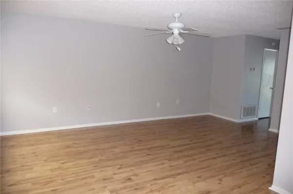 a view of a room with wooden floor and ceiling fan