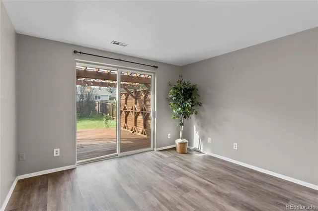 an empty room with wooden floor and floor to ceiling window