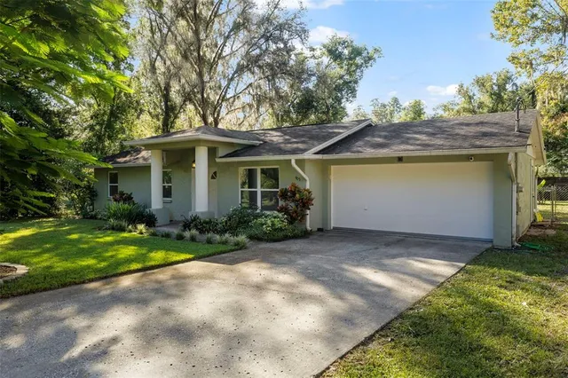 a view of a house with a yard and large tree