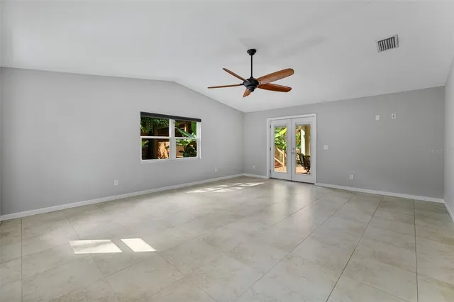 an empty room with windows and ceiling fan