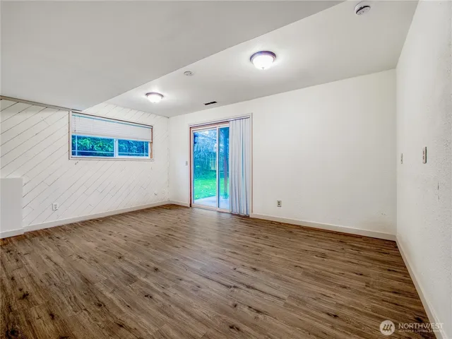 a view of an empty room with wooden floor and window
