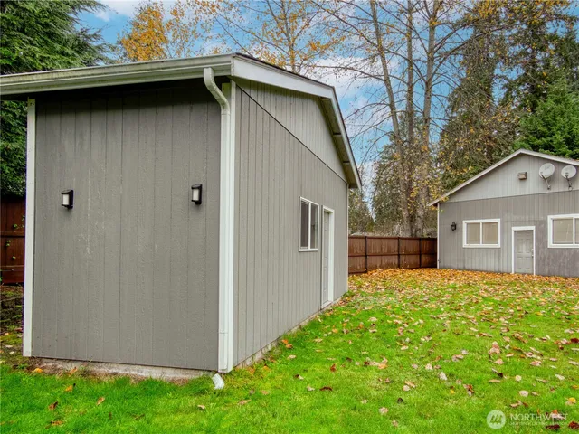 a backyard of a house with large tree and wooden fence