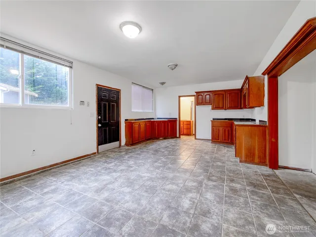 a view of empty room with a kitchen and refrigerator