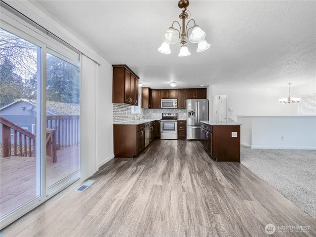 a large kitchen with a center island wooden floor and stainless steel appliances