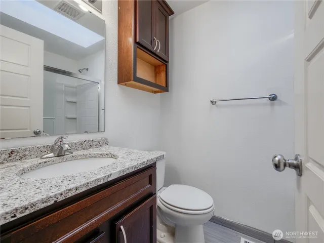 a bathroom with a granite countertop sink a toilet and a mirror
