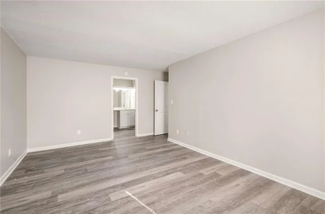 a view of an empty room with wooden floor and cabinets