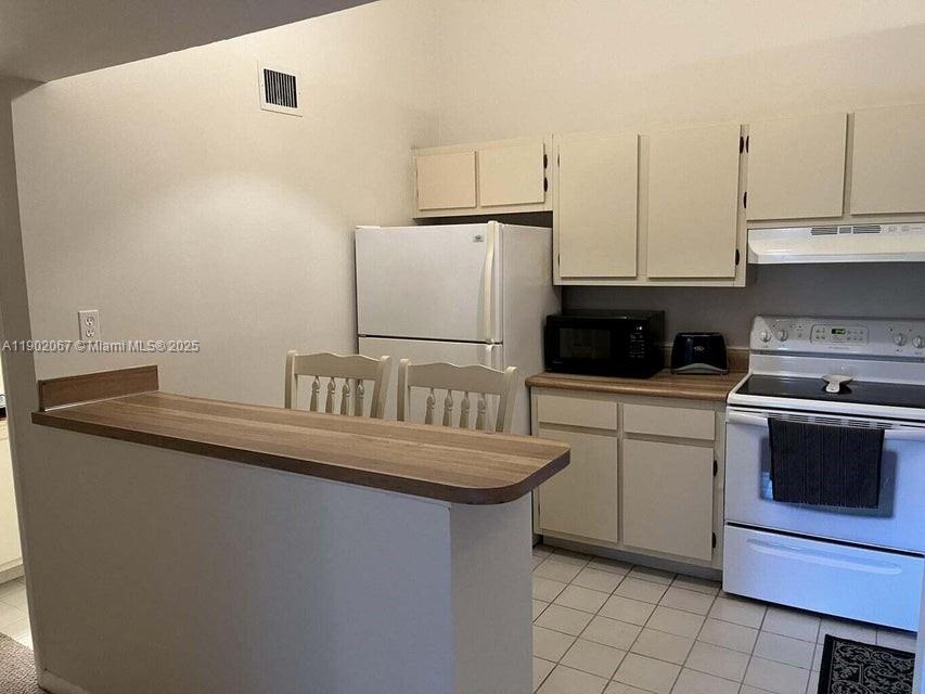 6327 Chasewood Drive, Unit G Jupiter, FL 33458 - Photo 12 of 35 a kitchen with granite countertop a sink a stove and cabinets
