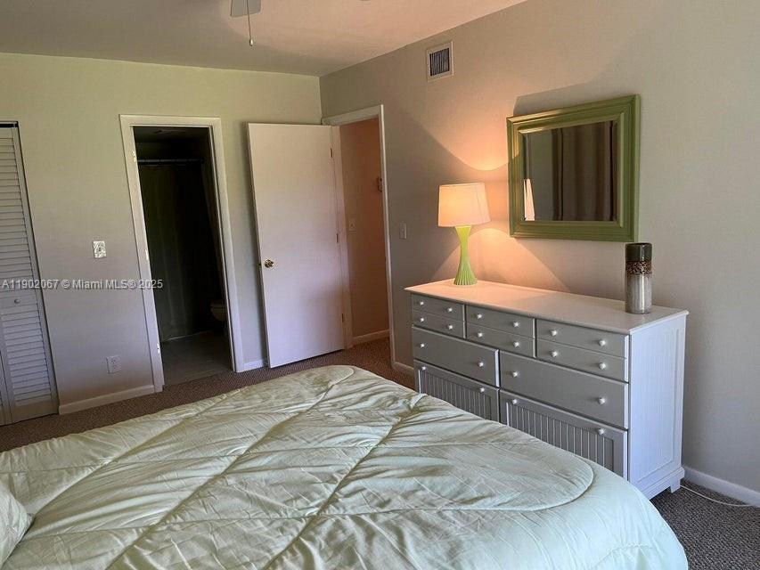 6327 Chasewood Drive, Unit G Jupiter, FL 33458 - Photo 25 of 35 a bedroom with a bed and a dresser