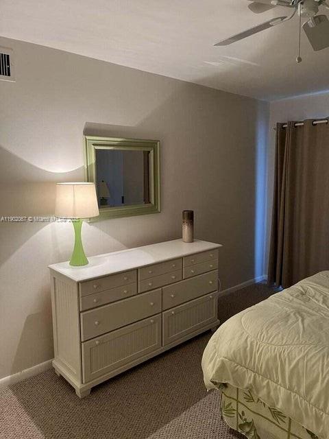 6327 Chasewood Drive, Unit G Jupiter, FL 33458 - Photo 26 of 35 a bedroom with a bed and a dresser