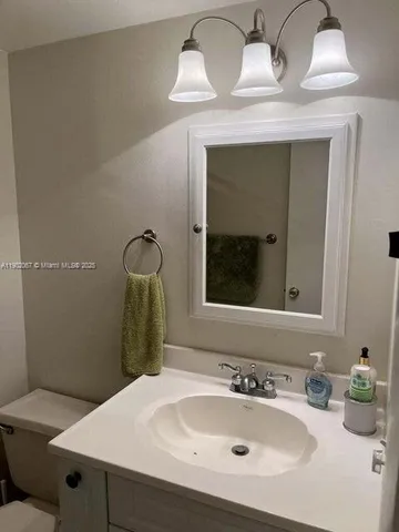 a bathroom with a sink vanity mirror and toilet