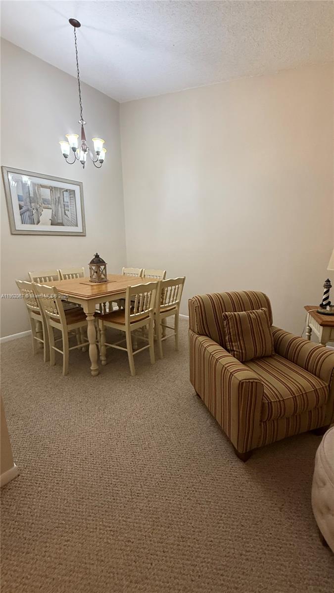 6327 Chasewood Drive, Unit G Jupiter, FL 33458 - Photo 6 of 35 a living room with furniture a chandelier and a dining table