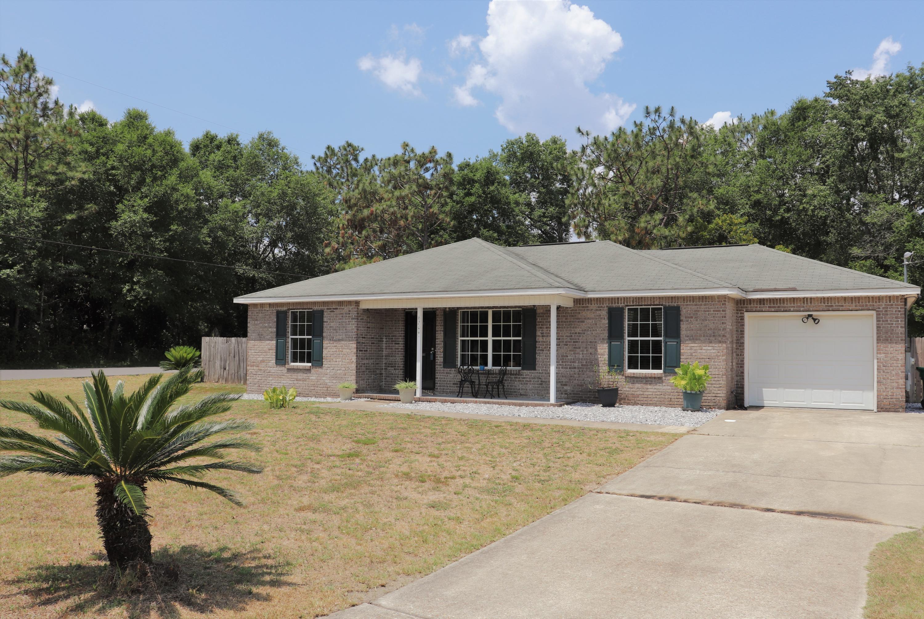 6204 Winstead Road Crestview, FL 32539 - Photo 3 of 37 a front view of a house with a garden and trees