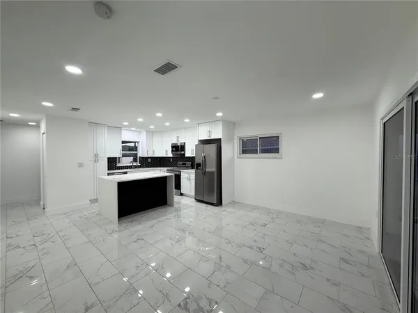 a large white kitchen with stainless steel appliances granite countertop a refrigerator and a stove top oven