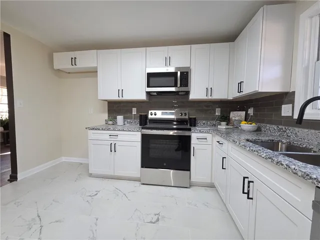 a kitchen with granite countertop a stove sink and cabinets