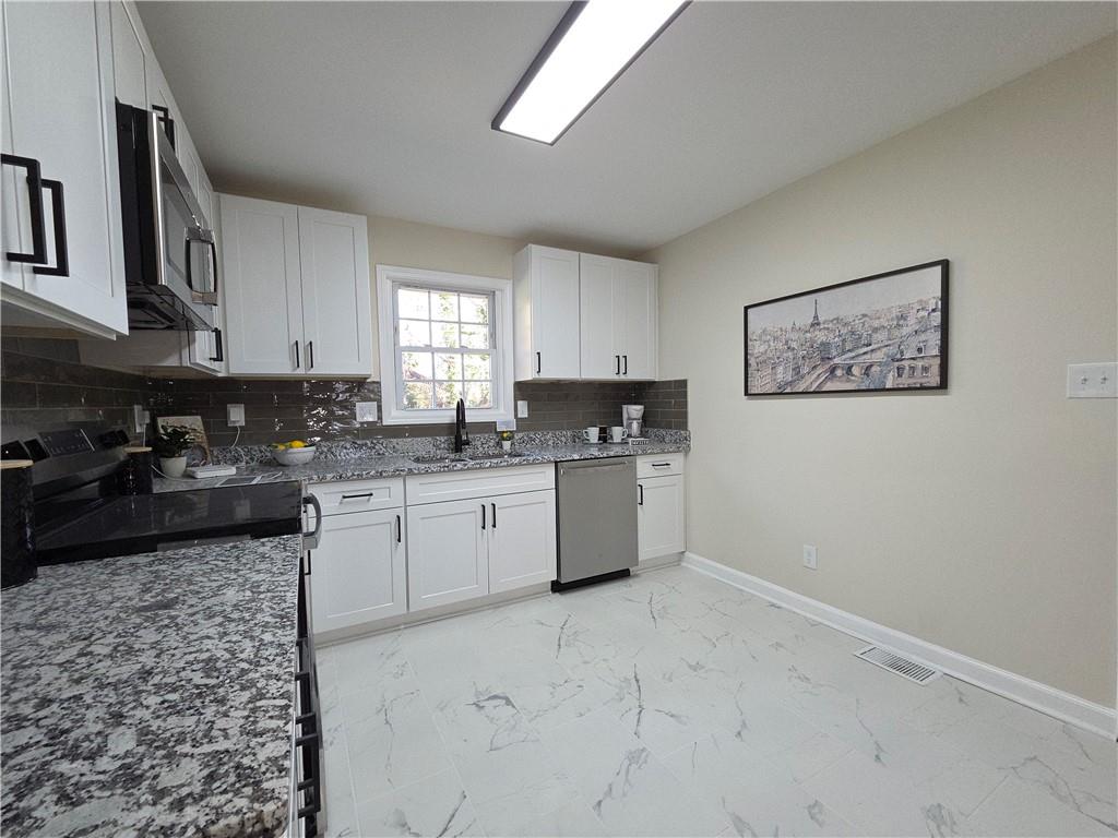 1576 South Gordon Road Southwest Austell, GA 30168 - Photo 12 of 33 a kitchen with granite countertop a stove a sink a window and white cabinets