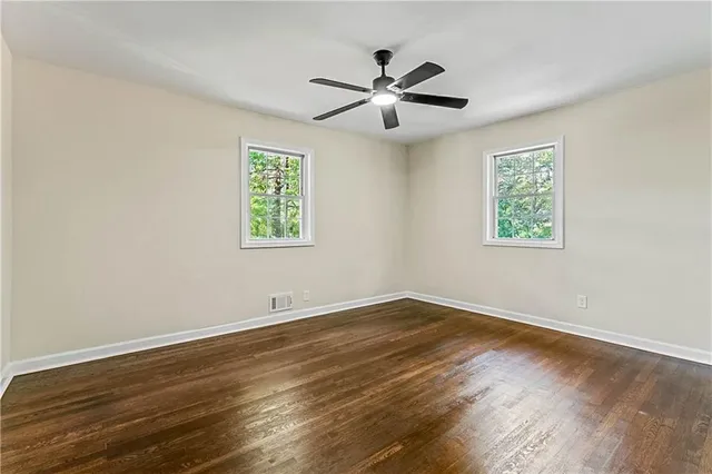 a view of an empty room with wooden floor and a window