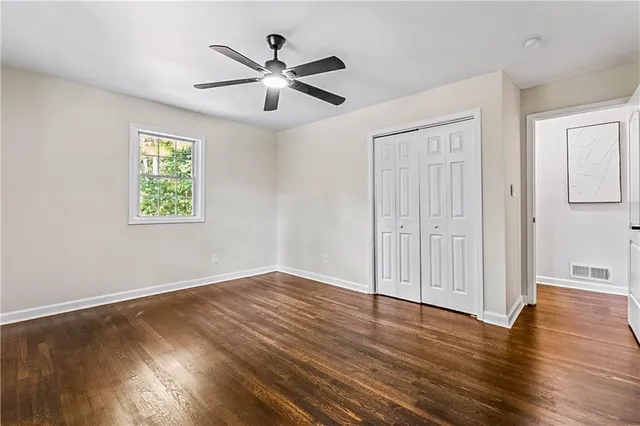 an empty room with wooden floor chandelier fan and windows