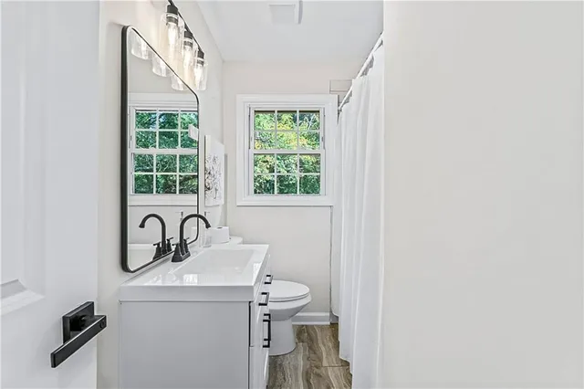 a bathroom with a sink a toilet and a window