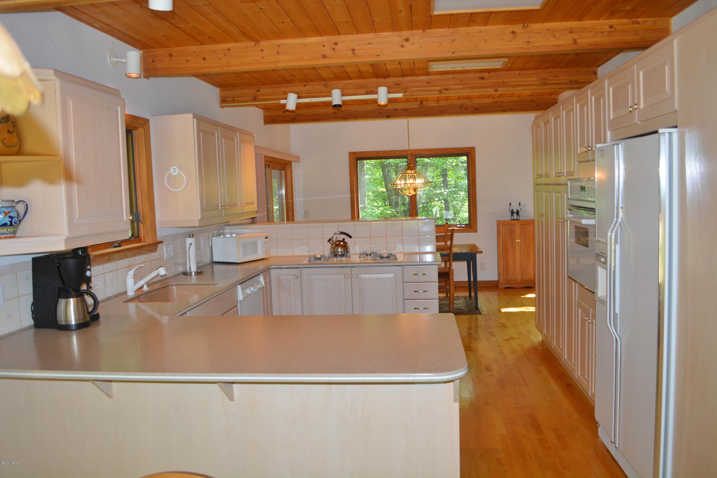537 Norton Road Otis, MA 01029 - Photo 5 of 25 a large kitchen with stainless steel appliances a large counter top a stove and a refrigerator