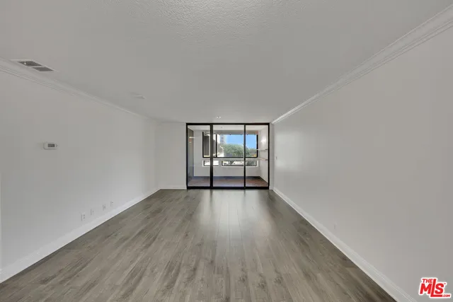 a view of an empty room with wooden floor and fence