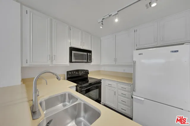 a kitchen with white cabinets and appliances