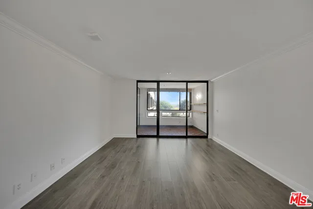 a view of an empty room with wooden floor and fan