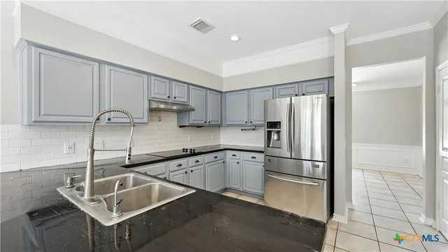a kitchen with stainless steel appliances granite countertop a sink refrigerator and cabinets