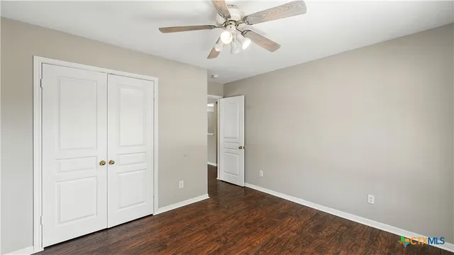 an empty room with wooden floor and fan