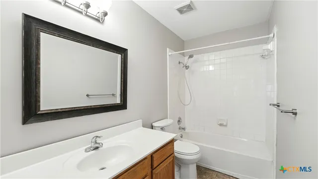 a bathroom with a bathtub shower sink vanity mirror and toilet