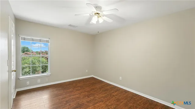 an empty room with a window and a fan
