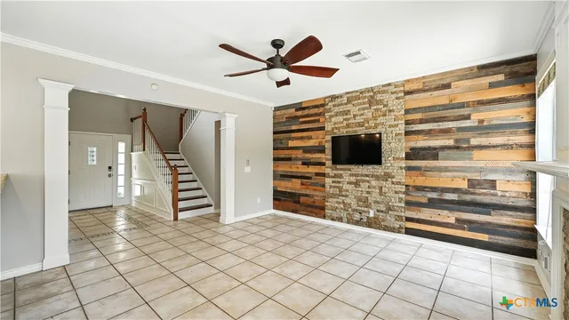 a view of an empty room with a fireplace and a ceiling fan