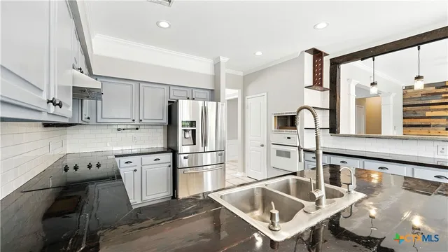 a kitchen with stainless steel appliances granite countertop a sink a stove and a refrigerator