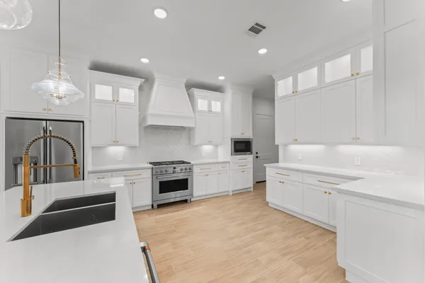 a large white kitchen with cabinets a sink and a stove