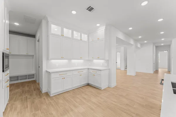 a large white kitchen with a sink dishwasher a stove and white cabinets with wooden floor