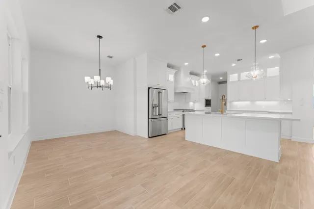 a view of a kitchen with a refrigerator a kitchen island white cabinetry and wooden floor