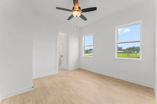an empty room with windows and fan