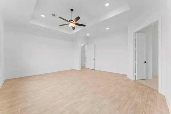 a view of an empty room and chandelier fan