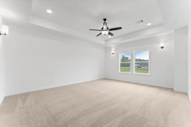 an empty room with windows and fan