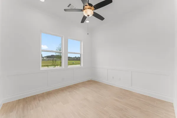 an empty room with windows and fan
